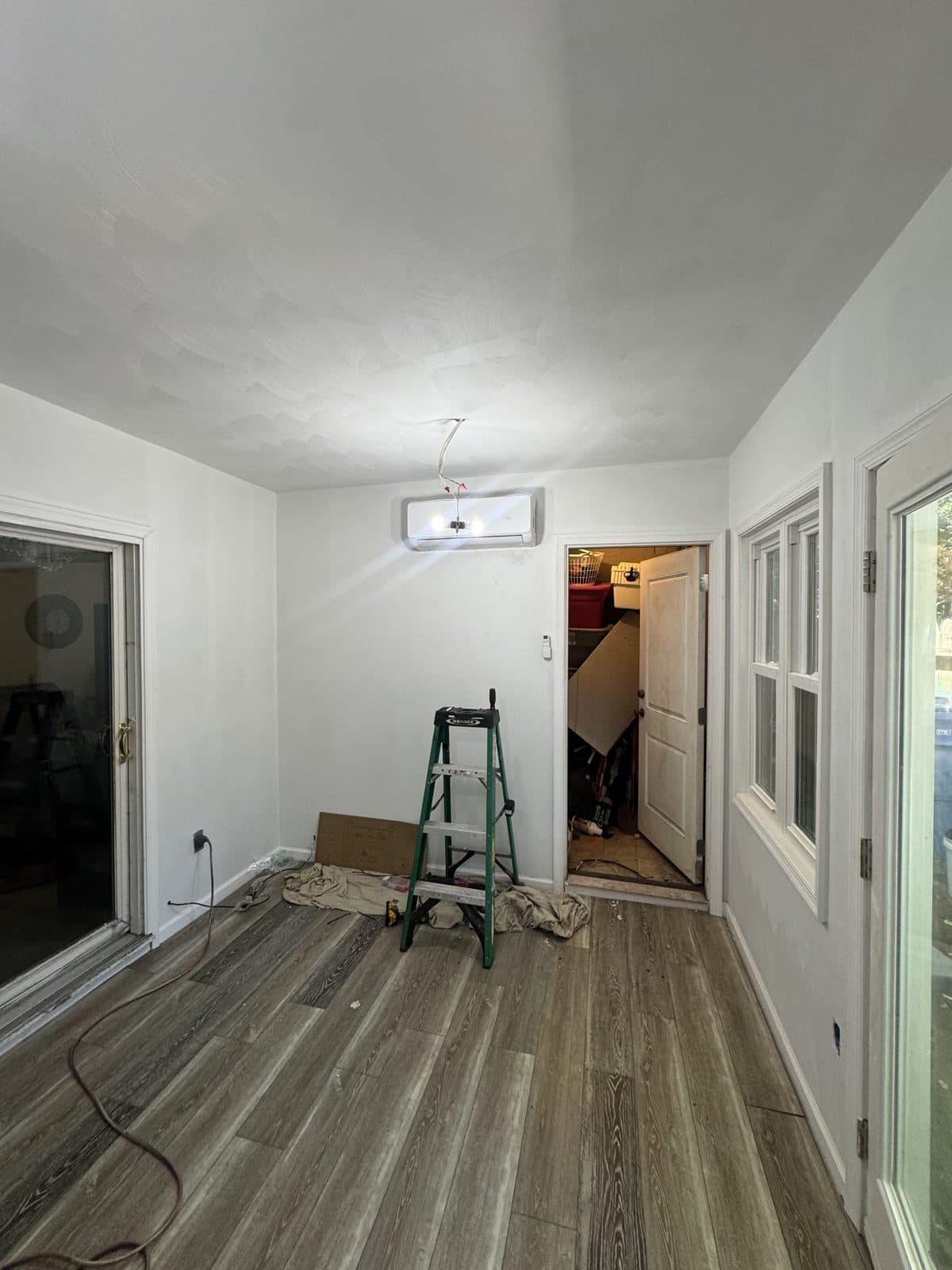 Wide view of the finished room showing the mini-split indoor unit above the doorway, new flooring and windows